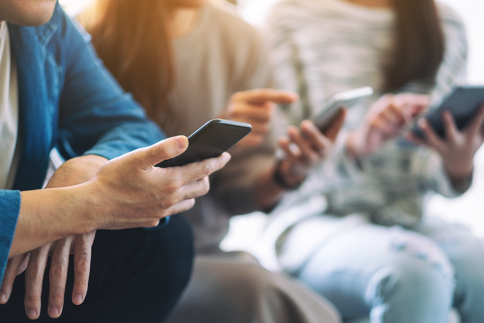A group of people sitting together, engrossed in their smartphones.